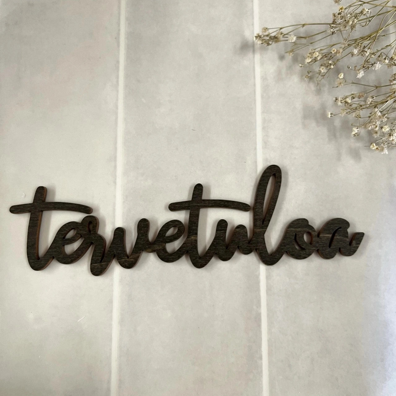 Musta puinen tervetuloakyltti rappukäytävään.