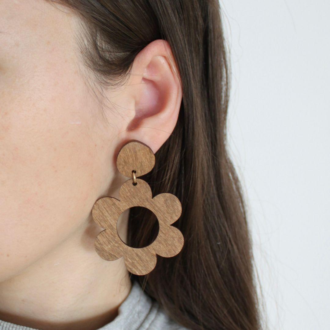 Ruskeat roikkuvat kukkakorvakorut puettuna.