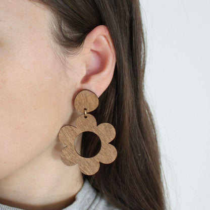 Ruskeat roikkuvat kukkakorvakorut puettuna.