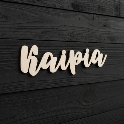 Puinen sukunimi-kyltti talonseinään tai oveen.