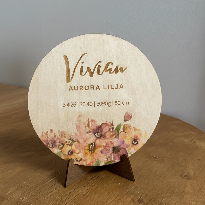 Puinen syntymätaulu vauvalle kukkakuviolla.