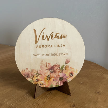 Puinen syntymätaulu vauvalle kukkakuviolla.