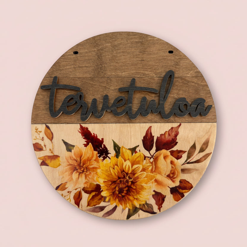 Puinen tervetuloa-kyltti syksyisellä kukkaviolla oveen.